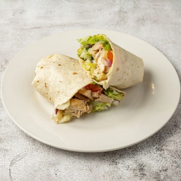 Two chicken wraps filled with lettuce, tomato, and onion, on a white plate.